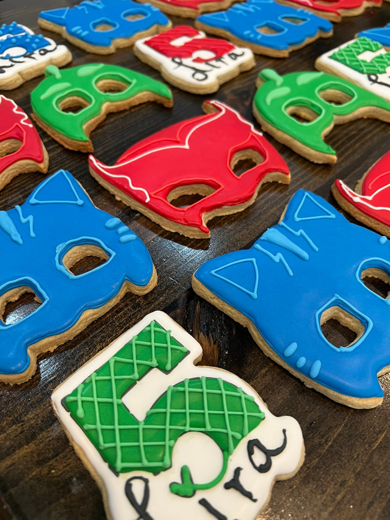 Colorful mask-shaped cookies on a wooden surface