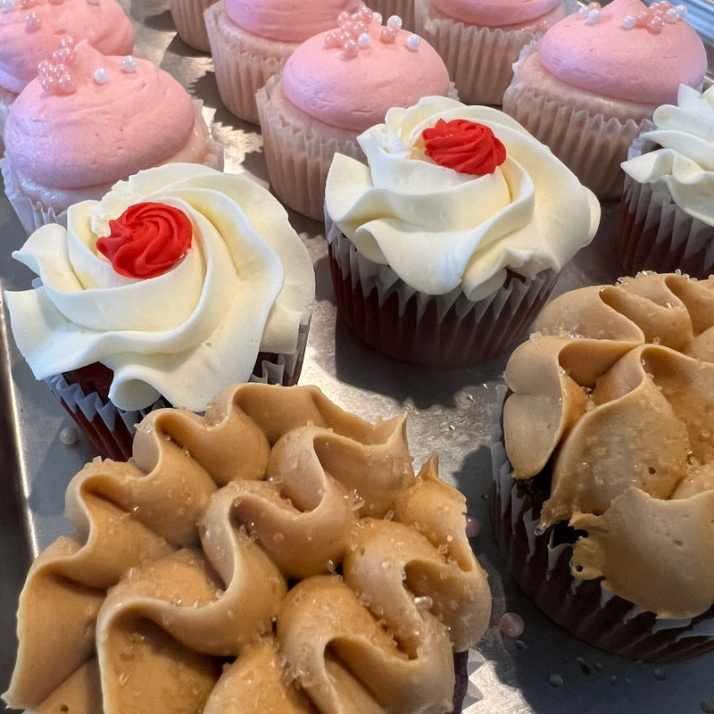 Assorted cupcakes with different frosting designs on a metal tray.